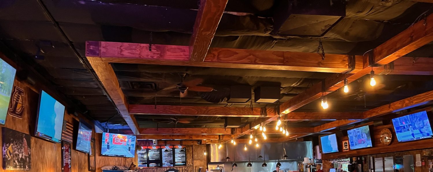 inside of bar with tvs kitchen booths and tables